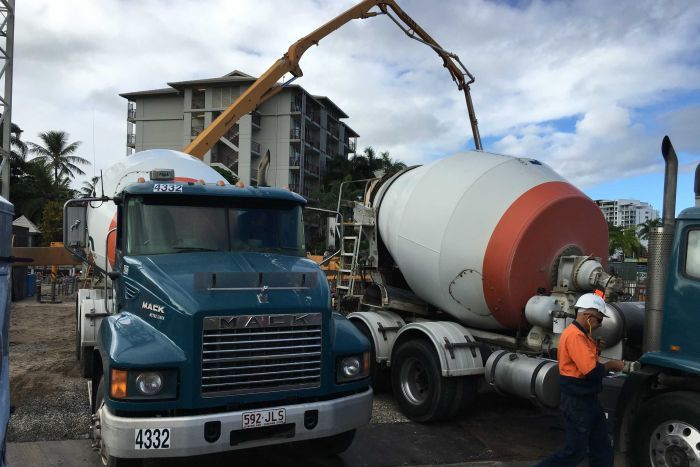 Two concrete trucks parked side-by-side wait their turn to pour concrete at the site of the Cairns Aquarium.