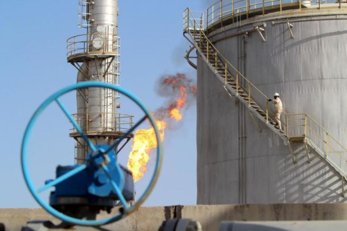 A work climbs the stairs at an oil storage facility in Iraq